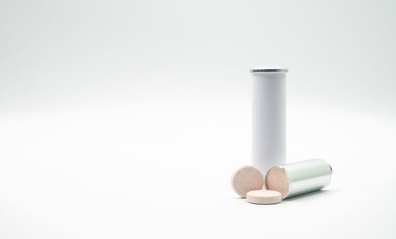Effervescent tables tube with blank label and copy space on white background. Calcium and vitamin C effervescent tablets are removed from the foil packaging. Vitamins, minerals and supplement concept.