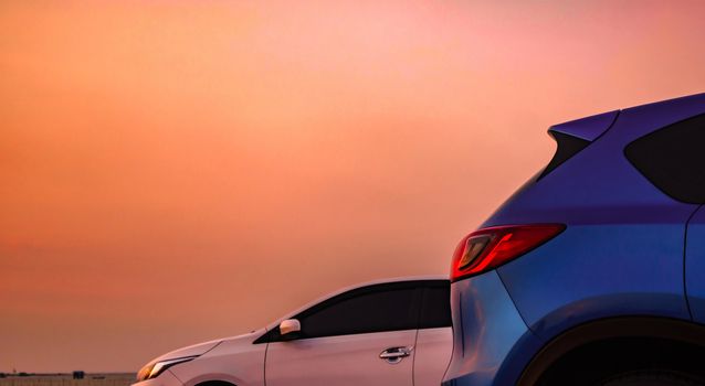 Blue compact SUV car with sport and modern design parked on concrete road by the sea at sunset. White Eco car. Environmentally friendly technology. Business success concept.