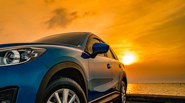 Blue compact SUV car with sport and modern design parked on concrete road by the sea at sunset. Environmentally friendly technology. Business success concept. Hybrid car. Automotive industry. Road trip concept.