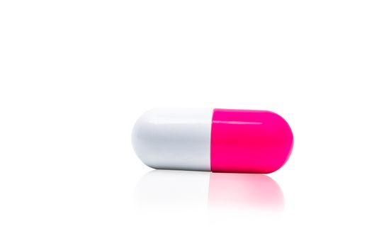 Pink, white capsule pills isolated on white background with shadow and copy space for text. Drug resistance concept. Antibiotics drug use with reasonable and global healthcare concept. Pharmacy sign and symbol. Pharmaceutical industry. Pharmacy background. Antibiotic or antimicrobial drug resistance. Health budgets and policy.