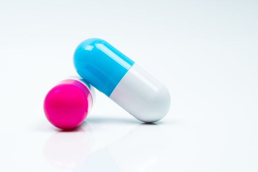 Two capsule pills isolated on white background. Global healthcare concept. Pharmacy sign and symbol. Pharmaceutical industry. Pharmacy background. Global healthcare concept. Antibiotic or antimicrobial drug resistance. Health budgets and policy. Blue-white and pink-white antibiotic capsule
