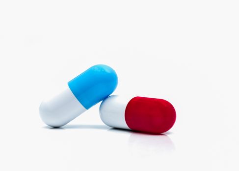 Two capsule pills isolated on white background. Global healthcare concept. Pharmacy sign and symbol. Pharmaceutical industry. Pharmacy background. Global healthcare concept. Antibiotic or antimicrobial drug resistance. Health budgets and policy. Blue-white and red-white antibiotic capsule.