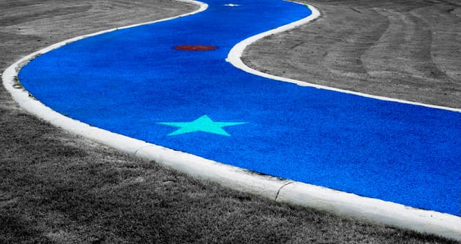 Blue abstract road with green star paint and gray grass as background