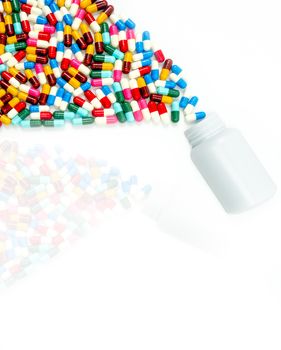 Antibiotic capsules spilling out of pill bottle on white background with copy space and shadows. Drug resistance concept. Antibiotics drug use with reasonable and global healthcare concept. Toxicology.