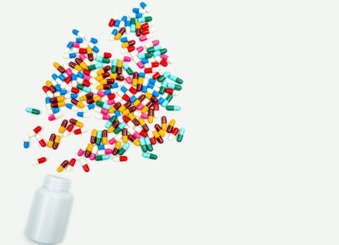 Pouring antibiotics capsule pills into plastic bottle on white background with copy space. Drug storage, antibiotic drug use with reasonable, health policy and health insurance concept. Pharmaceutical industry. Pharmacy background.