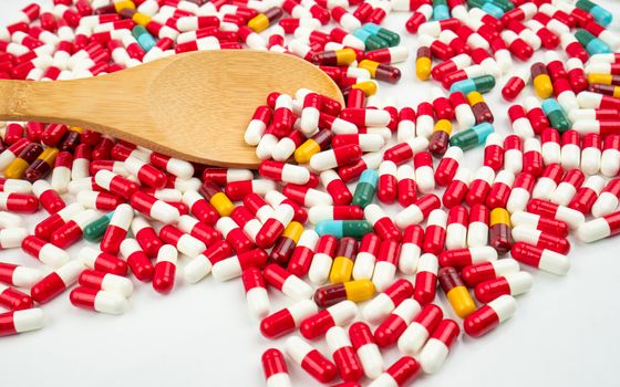 Colorful of antibiotic capsules pills and wood spoon on white background. Drug resistance concept. Antibiotics drug use with reasonable and global healthcare concept. Pharmaceutical industry. Pharmacy background.