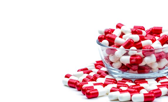 Red, white antibiotic capsules pills in glass bowl and some on white background with copy space. Drug resistance concept. Antibiotics drug use with reasonable and global healthcare concept.