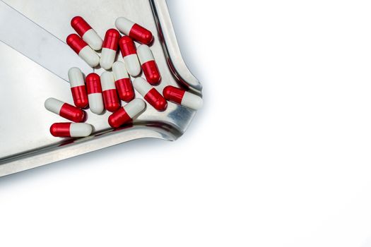 Top view of red, white antibiotic capsules pills on stainless steel drug tray. Drug resistance, antibiotic drug use with reasonable, health policy and health insurance concept. Pharmaceutical industry. Pharmacy background.