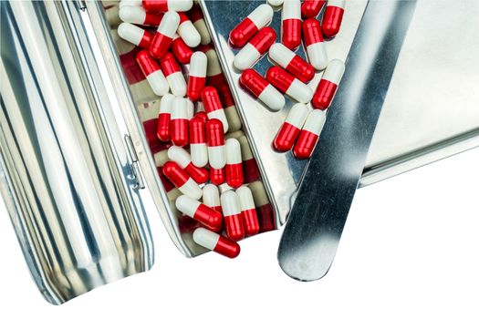 Top view of red, white antibiotic capsules pills on stainless steel drug tray. Drug resistance, antibiotic drug use with reasonable, health policy and health insurance concept. Pharmaceutical industry. Pharmacy background.