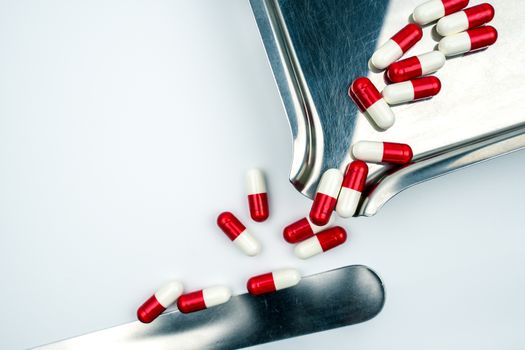 Top view of red, white antibiotic capsules pills on stainless steel drug tray. Drug resistance, antibiotic drug use with reasonable, health policy and health insurance concept. Pharmaceutical industry. Pharmacy background.