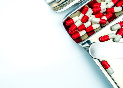 Top view of red, white antibiotic capsules pills on stainless steel drug tray. Drug resistance, antibiotic drug use with reasonable, health policy and health insurance concept. Pharmaceutical industry. Pharmacy background.