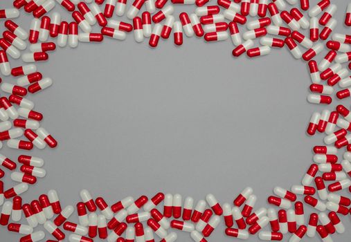Red, white antibiotic capsules pills on grey background with copy space. Drug resistance, antibiotic drug use with reasonable, health policy and budgets. Pharmaceutical industry. Capsules rectangle frame.