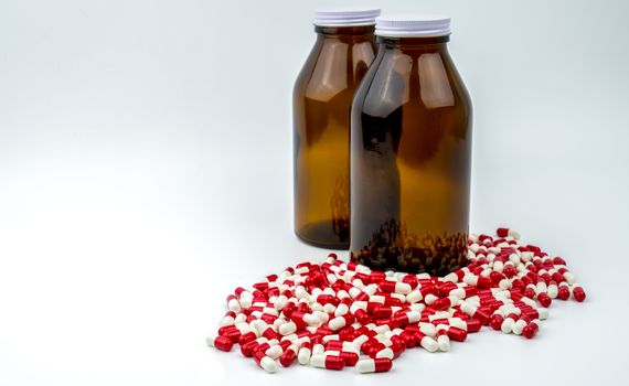 Colorful of antibiotic capsules pills with two amber glass bottles isolated on white background. Drug resistance, antibiotic drug use with reasonable. Pharmaceutical industry. Pharmacy background. Antibiotics drug overuse. Health budgets and policy.