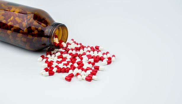 Colorful of antibiotic capsules pills with two amber glass bottles isolated on white background. Drug resistance, antibiotic drug use with reasonable. Pharmaceutical industry. Pharmacy background. Antibiotics drug overuse. Health budgets and policy.