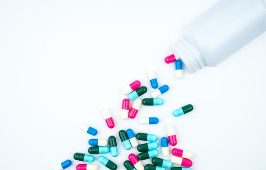 Antibiotic capsules spilling out of pill bottle on white background with copy space, just add your own text. Antibiotic drug use with reasonable concept. Antimicrobial drug overuse. Pharmaceutical industry. Pharmacy background. Global healthcare. Health budgets and policy concept.