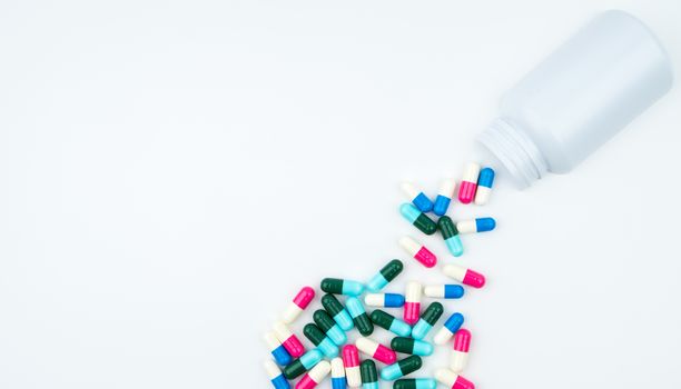 Antibiotic capsules spilling out of pill bottle on white background with copy space, just add your own text. Antibiotic drug use with reasonable concept. Antimicrobial drug overuse. Pharmaceutical industry. Pharmacy background. Global healthcare. Health budgets and policy concept.