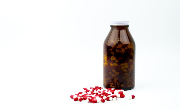 Red, white antibiotic capsules pills and amber glass bottle isolated on white background with copy space and blank label. Drug resistance, antibiotic drug use with reasonable. Pharmaceutical industry. Pharmacy background. Global healthcare. Antimicrobial drug overuse.