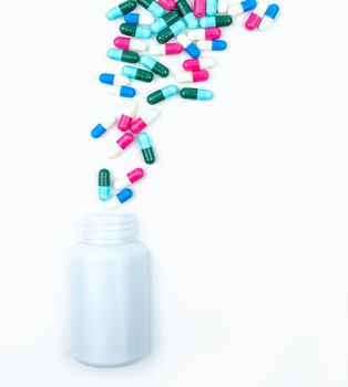 Pouring antibiotics capsule pills into plastic bottle isolated on white background with copy space. Drug storage, antibiotic drug use with reasonable. Health budgets and policy. Pharmaceutical industry. Pharmacy background. Antimicrobial drug overuse.