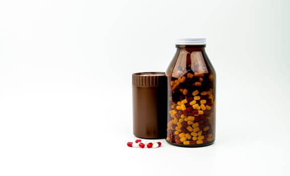 Red, white antibiotic capsules pills and two amber bottles isolated on white background with copy space and blank label. Drug resistance, antibiotic drug use with reasonable, health policy concept. Pharmaceutical industry. Pharmacy background.