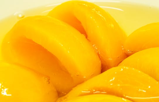 Closeup canned peach halves in syrup. Yellow fruit.