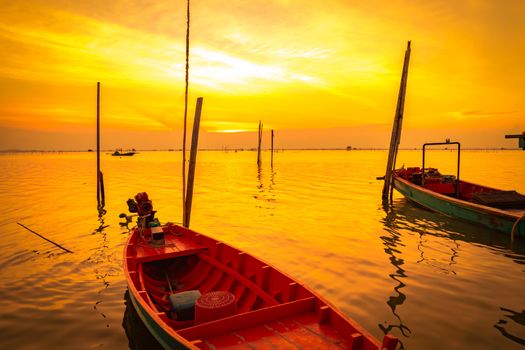 Fisherman's boat floating in the sea near bamboo pole at sunset in Thailand.