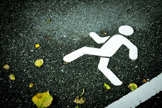 White painted sign on asphalt. Pedestrian lane and yellow dry leaves. Skip over obstacles.