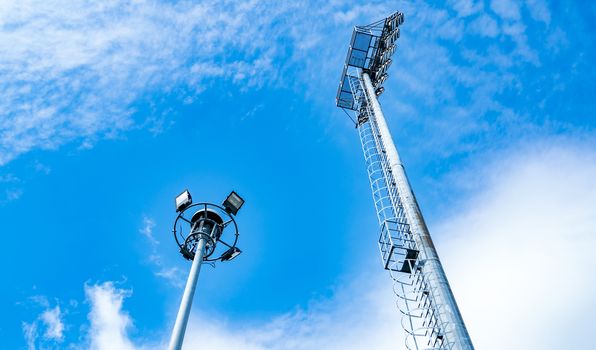 Sport lights of the stadium on beautiful blue sky and white clouds. Copy space