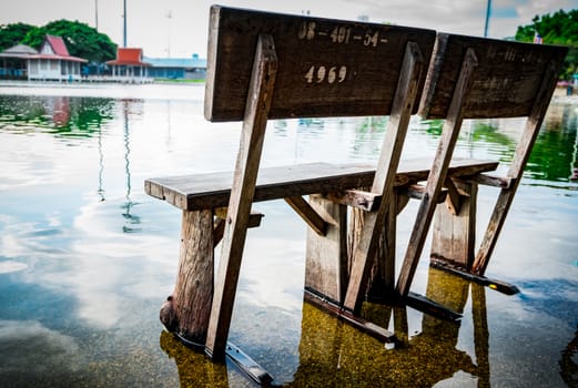 Old wooden bench Installed on the cement floor in the temple after rain, flooded the ground. The sky is bright after rain.