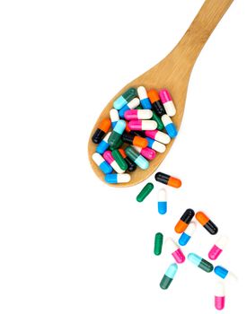 Colorful of antibiotics capsule pills in wooden spoon are spilling isolated on white background with copy space and clipping path. Antibiotic drug use with reasonable and health insurance concept.