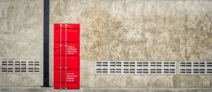 Closed red iron door on concrete wall with ventilator