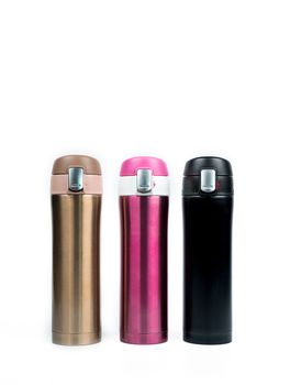 Gold, pink and black thermos bottles isolated on white background with copy space. Beverage container. Coffee and tea bottle.