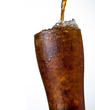 Soft drink with crushed ice cubes in glass isolated on dark background with copy space. There is a drop of water on the transparent glass surface.
