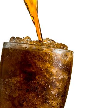 Soft drink pouring to glass with ice isolated on white background with clipping path and copy space. There is a drop of water on the transparent glass surface.