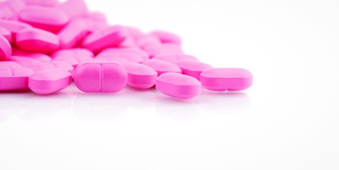 Pile of pink tablets pill isolated on white background. Norfloxacin 400 mg for treatment cystitis. Antibiotics drug resistance. Pink pills symbol of romantic love and healthcare for perfect couple.