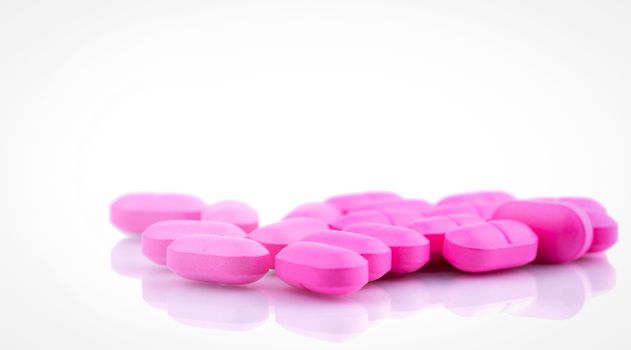 Pile of pink tablets pill isolated on white background. Norfloxacin 400 mg for treatment cystitis. Antibiotics drug resistance. Pharmaceutical industry. Pharmacy background. Global healthcare.