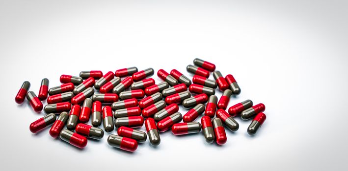 Pile of red and grey capsule pills isolated on white background with copy space. Flunarizine : drug for migraine prophylaxis treatment. Global healthcare concept. Pharmaceutical industry concept.