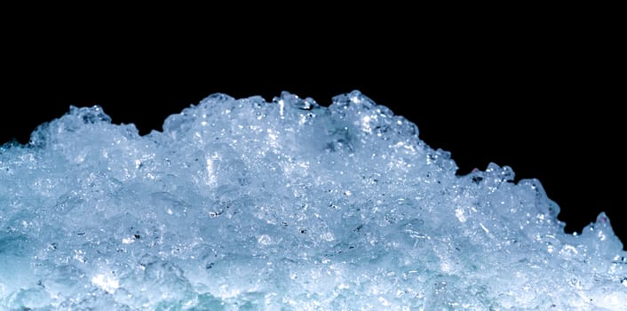 Pile of crushed ice cubes on dark background with copy space. Crushed ice cubes foreground for beverages.