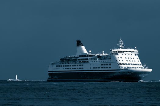 Passenger ship sailing from the sea in the morning. Toned dark blue