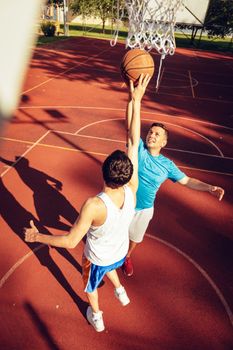 Two street basketball players having training outdoor. They are making a good action.