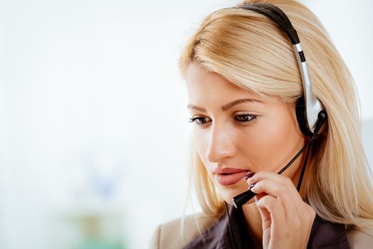 Beautiful young woman with a headset on her head at the office.