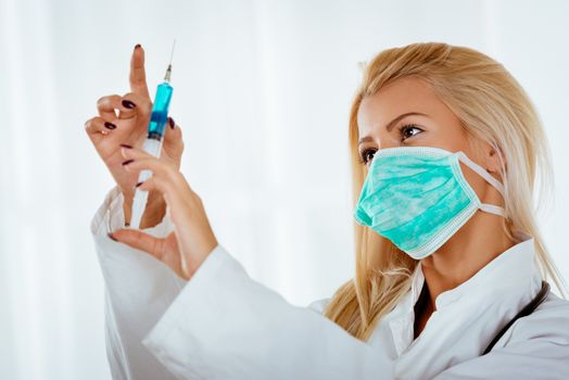 Beautiful young woman in a white coat preparing an injection of anesthesia.