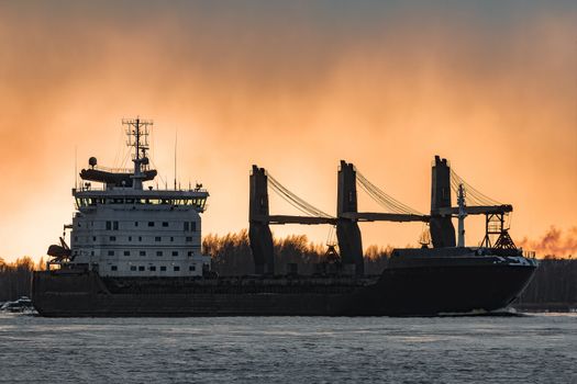 Black bulk carrier sailing to the sea in cold winter