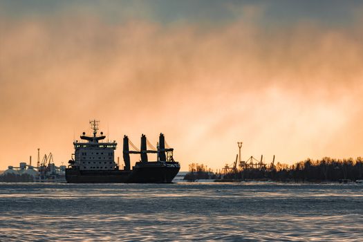 Black bulk carrier sailing to the sea in cold winter