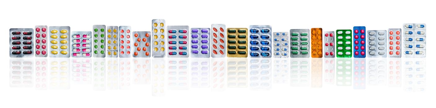 Many of colorful pills in blister packs in a row isolated on white background with copy space. Pharmaceuticals industry. Healthcare education in hospital. Pharmacology. Painkiller and antibiotics