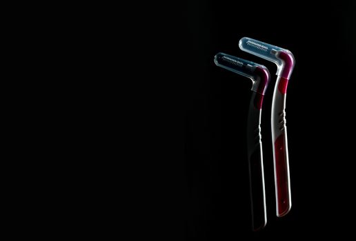 Two interdental brush with cover isolated on dark background with copy space. Dental care concept. Equipment for get rid of food stuck in teeth