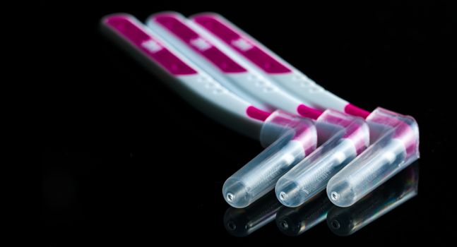 Three interdental brush with cover isolated on dark background with copy space. Dental care concept. Equipment for get rid of food stuck in teeth