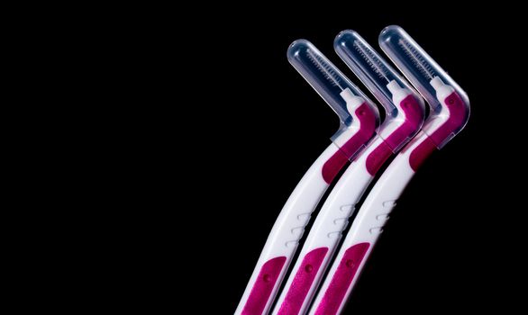 Three interdental brush with cover isolated on black background with copy space for text. Dental care concept. Equipment for get rid of food stuck in teeth