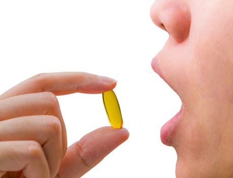 Young woman hand hold fish oil capsule near open mouth. Woman taking omega-3 pills. Vitamins and supplements concept.