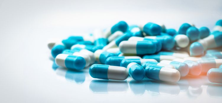 Selective focus on blue and white capsules pill spread on white background with shadow. Global healthcare concept. Antibiotics drug resistance. Antimicrobial capsule pills. Pharmaceutical industry.