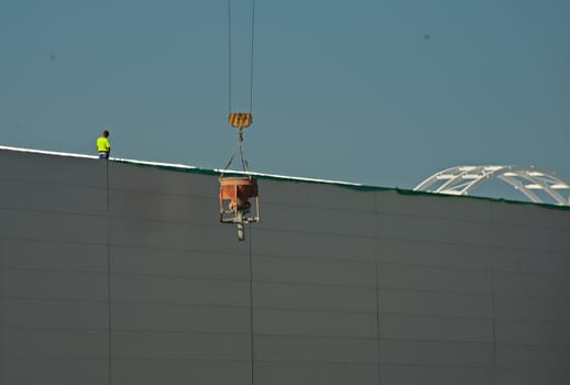 NOVI SAD, SERBIA - July 14th: Worker supervising crane lifting weight